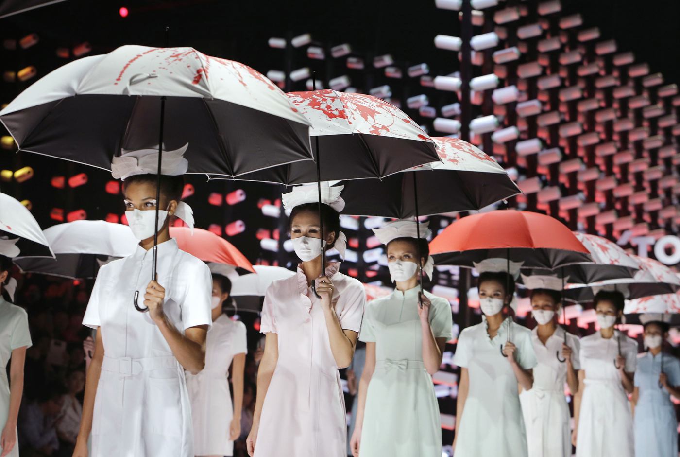 Models wearing masks hold umbrellas as they perform during the TORAY Liu Wei Collection segment at China Fashion Week in Beijing on Oct. 30.