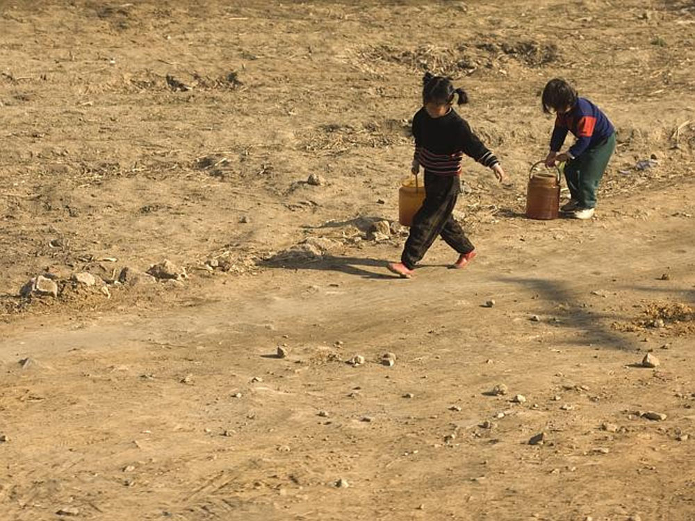 Children working and collecting materials outside--an image North Korea forbids because child labor implies poverty.