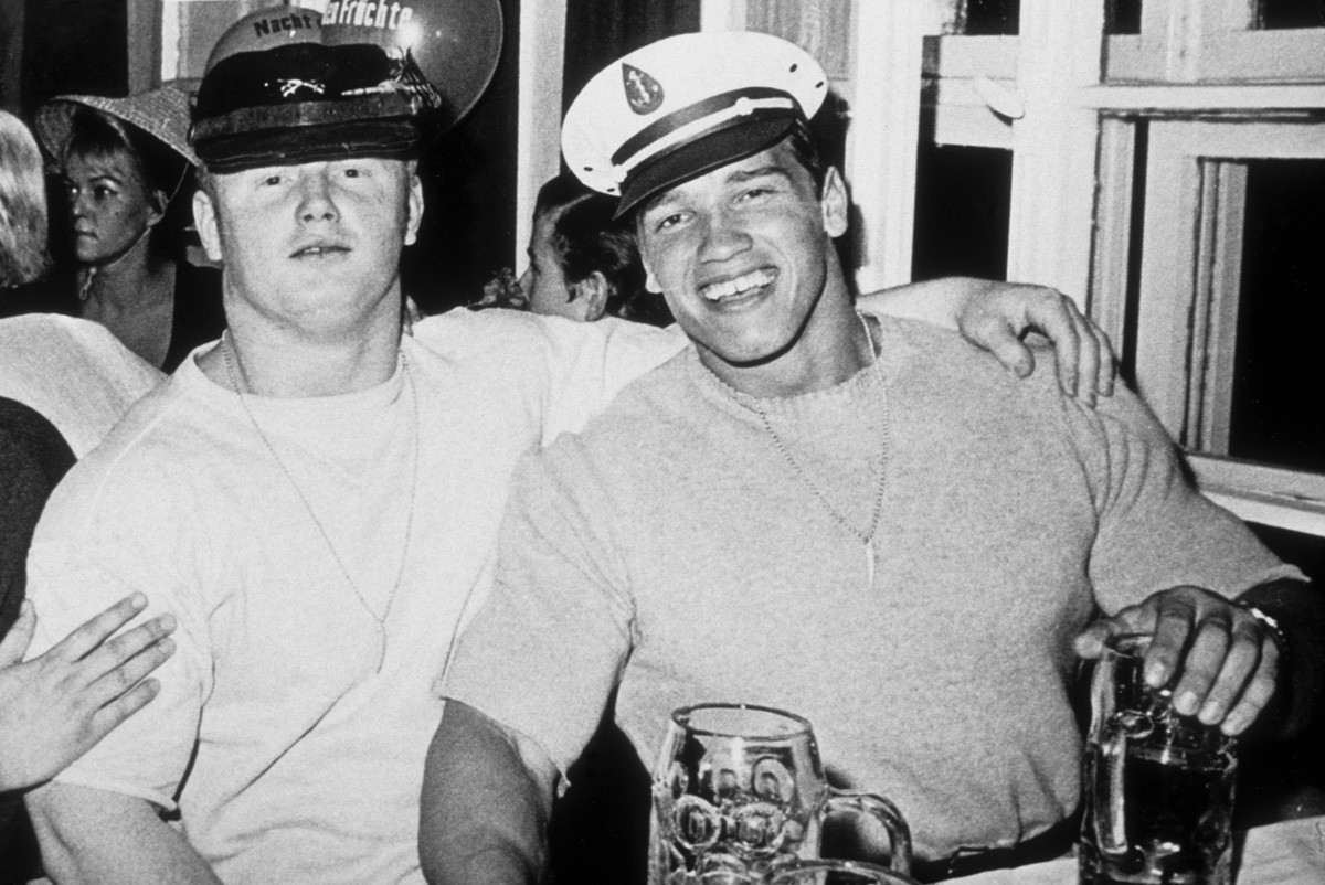 A young Arnold Schwarzenegger enjoys Oktoberfest with a friend in 1967, Munich, West Germany.