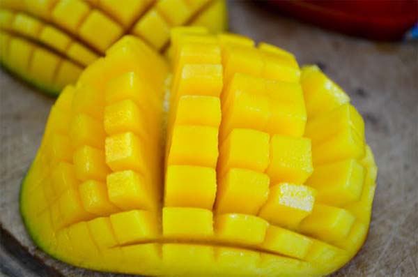 Easily dice a mango by keeping the fruit attached to the skin, cutting a grid in it with a knife and then inverse the slices and cut off the cubes.