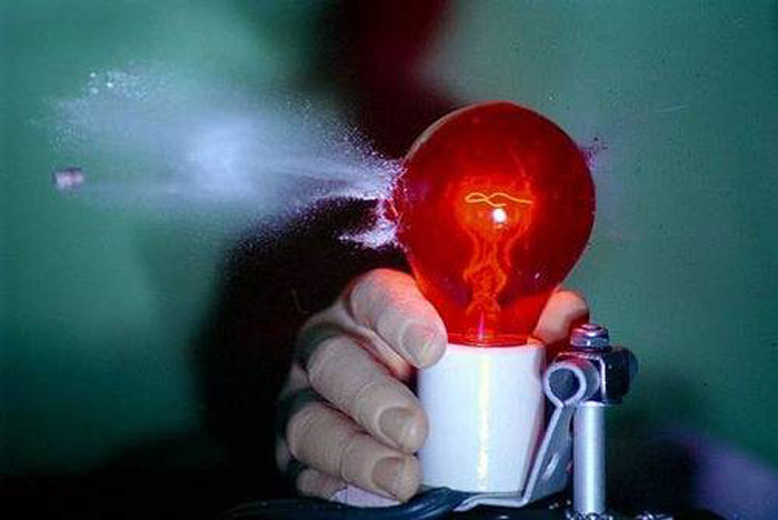 Bullet through a red light bulb the hand is made of rubber