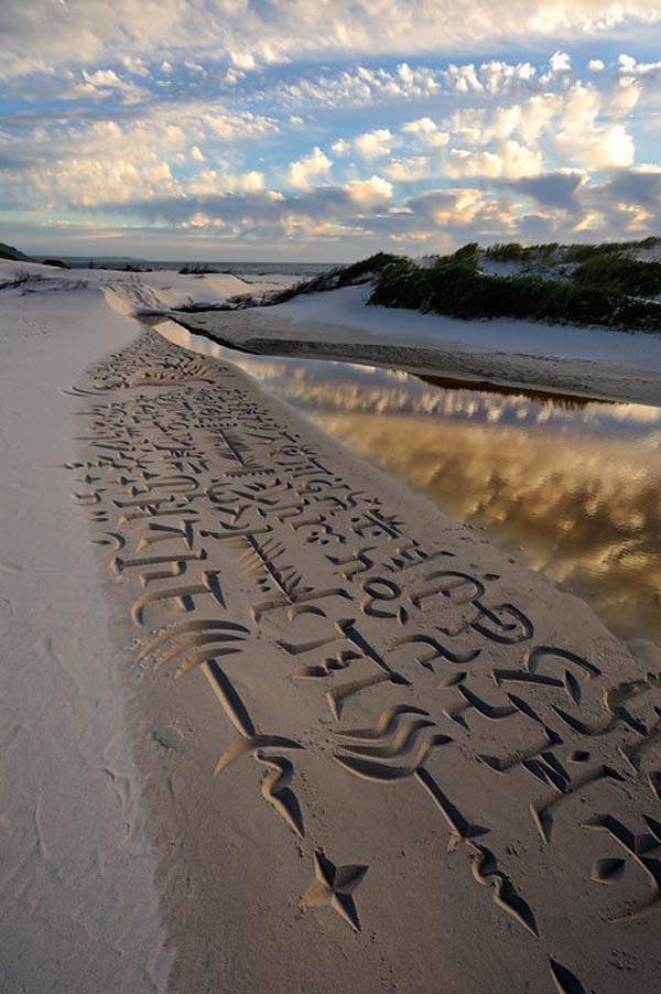 After carving the letters in the sand, he quickly photographs them.