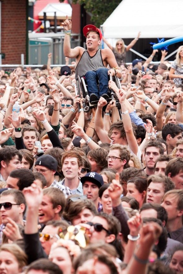 Crowd helps wheelchair boy enjoy show from above.