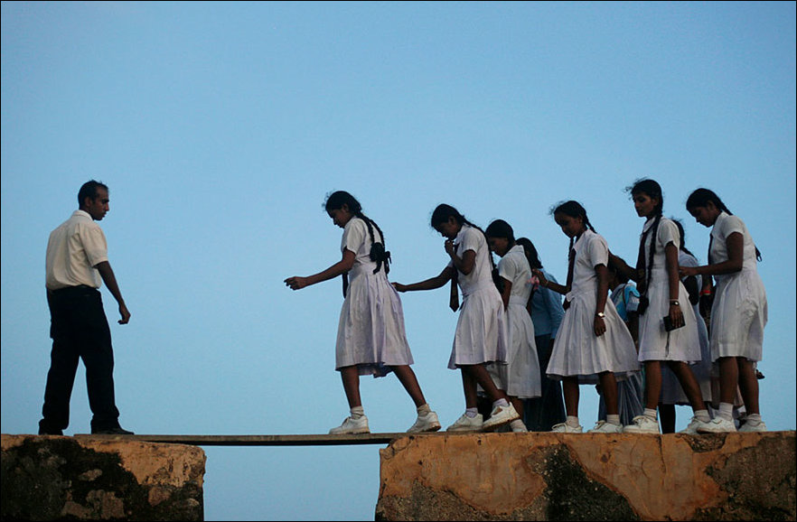 Girls go to school in Galle across a fort wall of the 16th century in Sri Lanka.