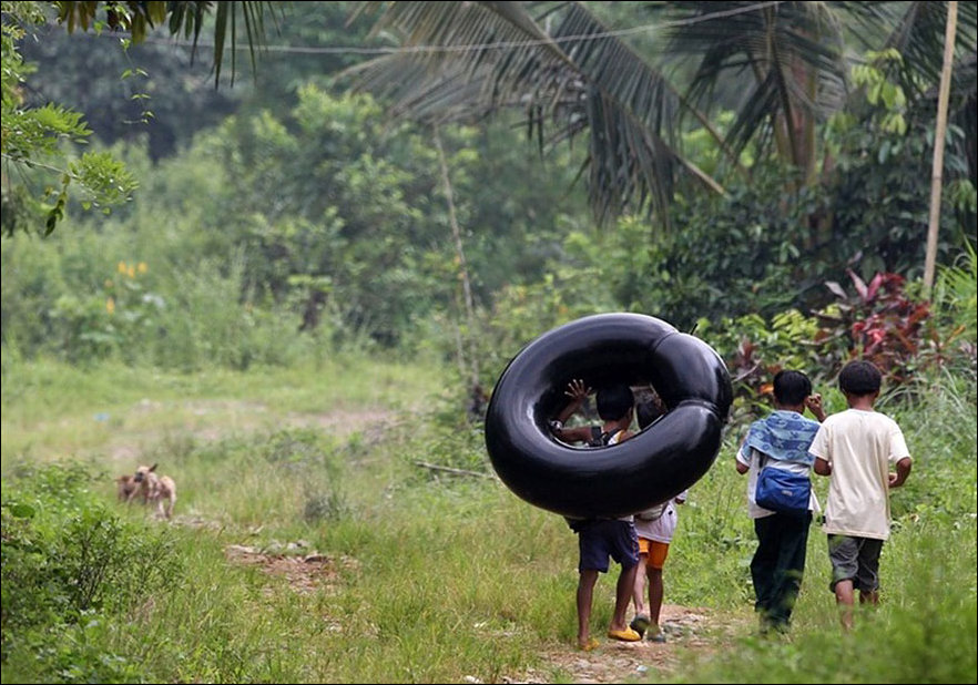 Floating to school on  inner tubes in the Philippines.
