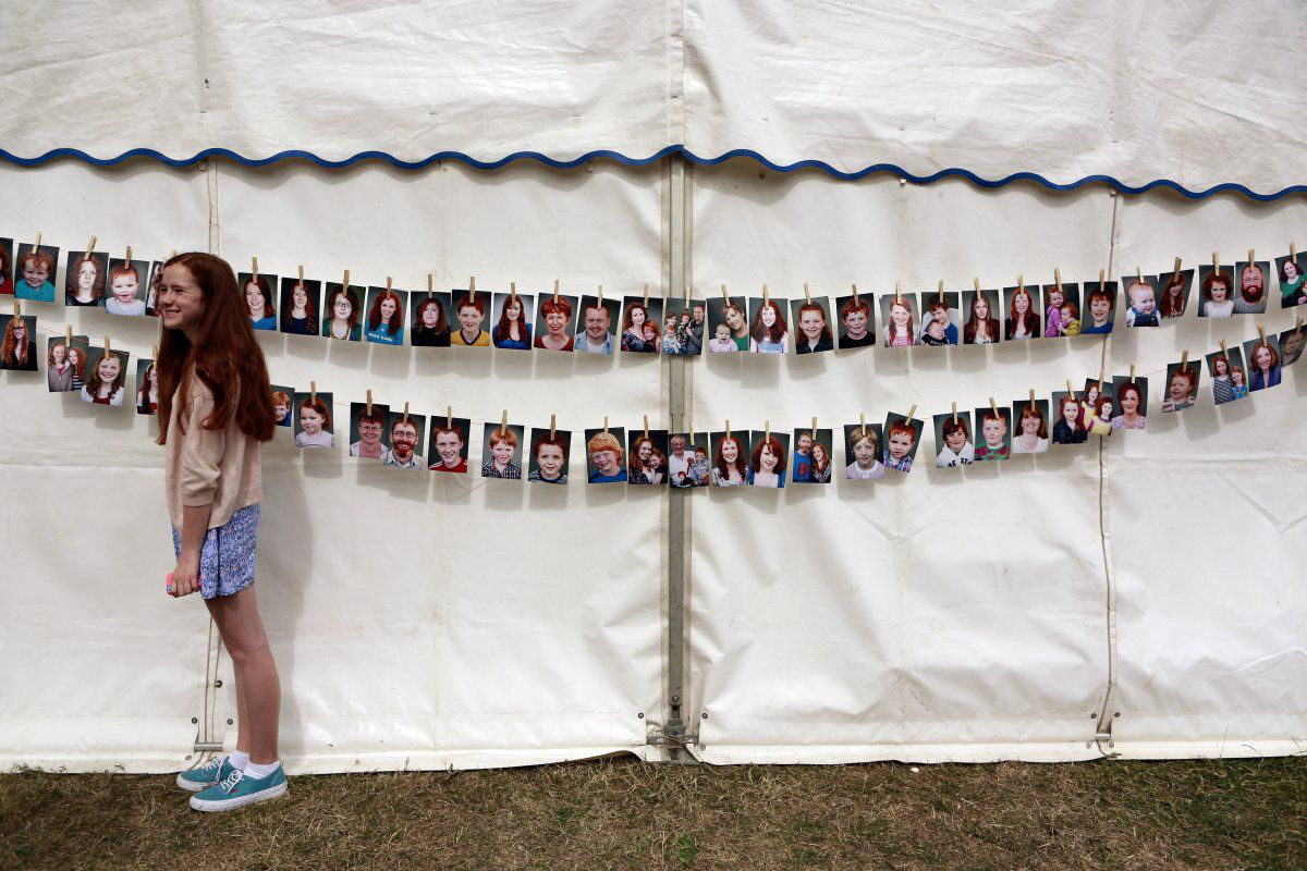 A girl poses by portraits of participants in the Irish Redhead Convention in County Cork. The annual festival celebrates the glory that is red hair.