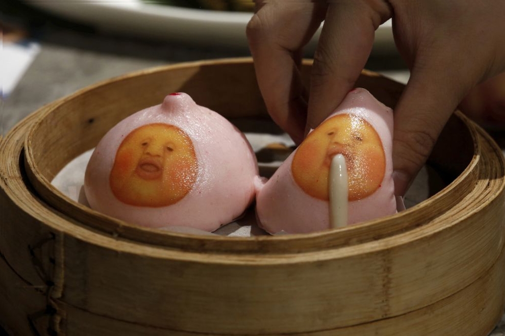 A milk custard bun made to resemble one of the popular Japanese "Kobitos" characters is squeezed during a display for the photographer at Dim Sum Icon restaurant in Hong Kong