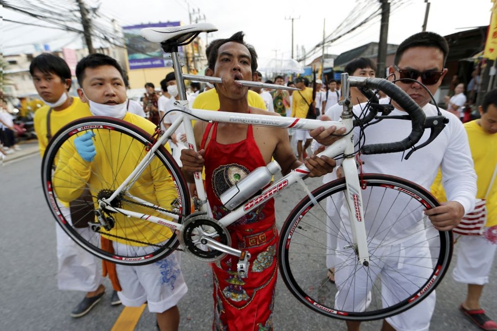 A devotee of the Chinese Samkong Shrine walks with a bike pierced on his mouth during a procession celebrating the annual vegetarian festival in Phuket