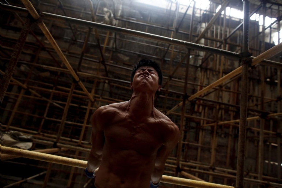 Worker Shi Shenwei performs a high bar routine on a scaffolding at the construction site of a Buddhist temple in the village of Huangshan, near Quanzhou, Fujian Province, China, September 28, 2016.
