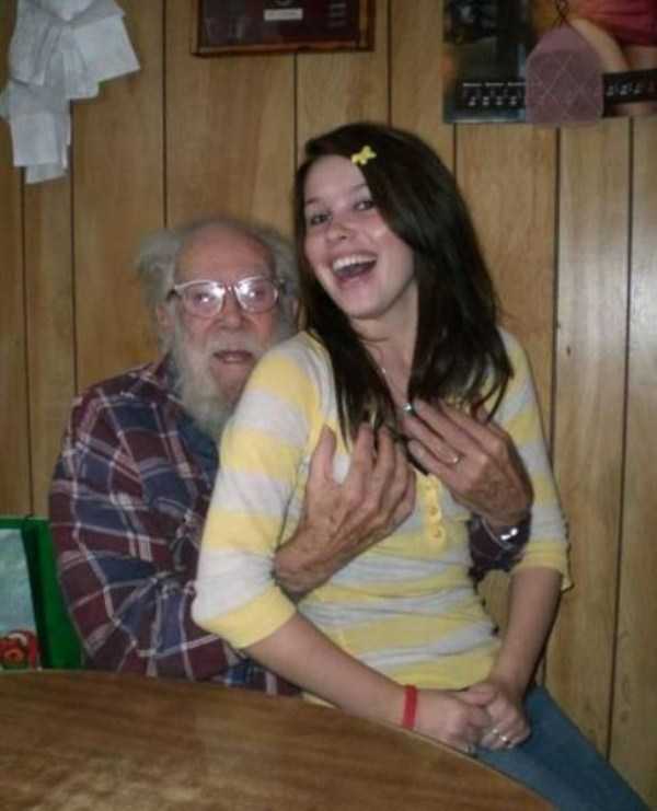 Cringeworthy picture of woman girl sitting on grandpa's lap and he is cupping her breasts very inappropriately and she is laughing.