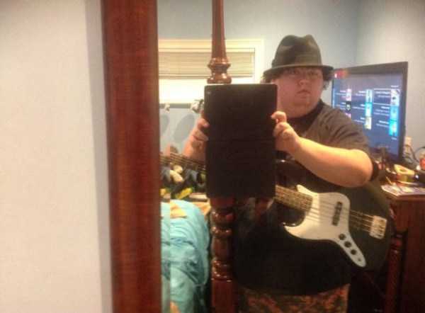 Very cringeworthy selfie of fat man with fedora and an electric guitar taking the pic on his ipad to the mirror.