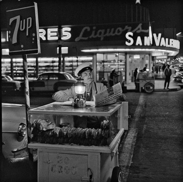 A taco vendor reads the paper at night in Tijuana, Mexico in 1964.