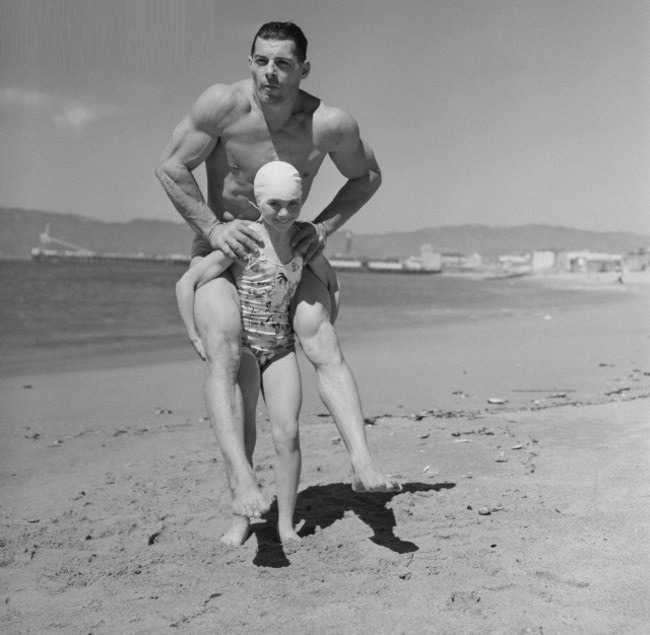 Patricia O’Keefe, a 10 year old 64 pound bodybuilder gives her 200 pound father a piggyback ride at the beach in California, US in 1940.