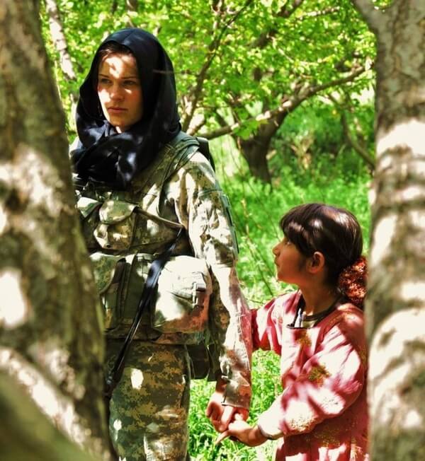 A female soldier holding hands with a little Afghan girl