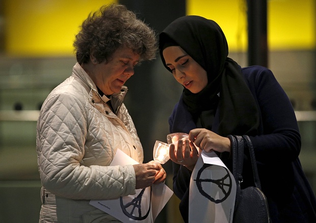 Two women light candles to commemorate the victims of the Paris attacks in France.