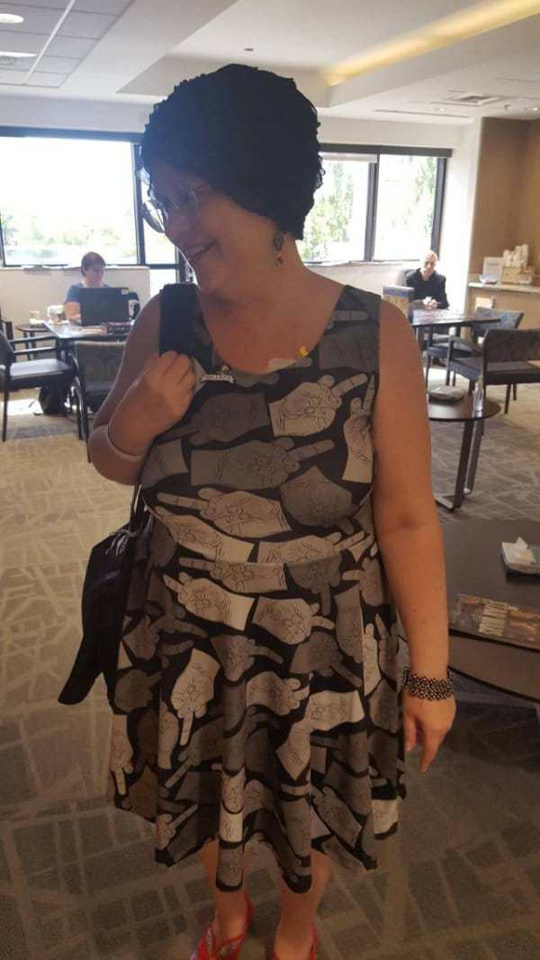 Woman wearing a dress with all middle fingers on the pattern.