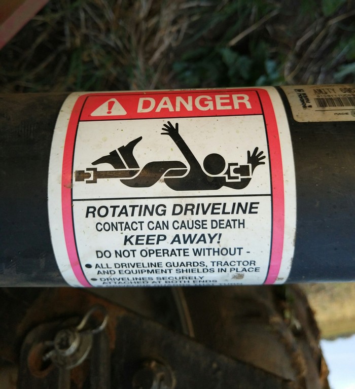Warning label on a rotating drive line with slightly humorous illustration