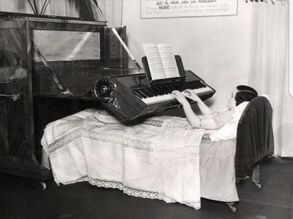 black and white pic of a woman in bed with a piano organ set up