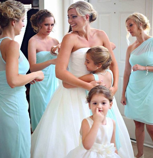 Brides and bridesmaids getting ready and one of the kids in the picture is picking her nose.