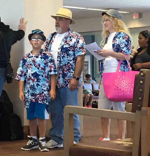 Family is wearing all the same hawaiian shirts.