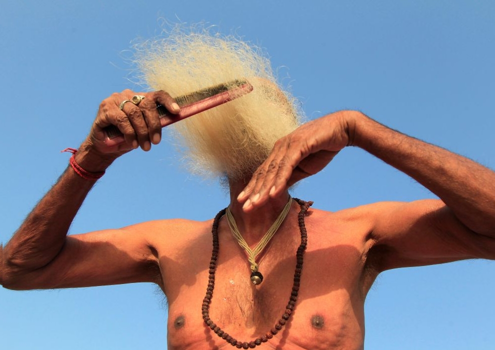 A Sadhu or Hindu holy man combs his beard after taking a dip in the waters of Shipra river during Simhastha Kumbh Mela in Ujjain