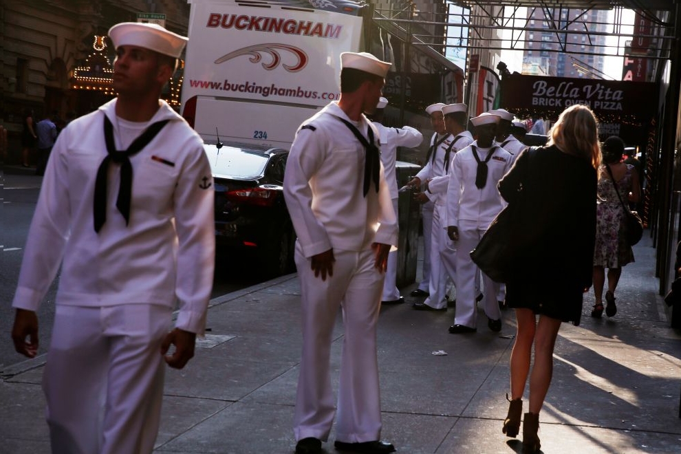 U.S. Navy sailors watch a woman walk past as they walk through Times Square during Fleet Week in New York
