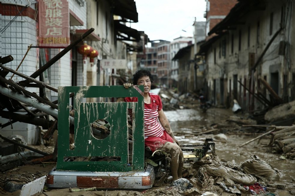 A woman sits on the ruins after typhoon Nepartak swept through Minqing county