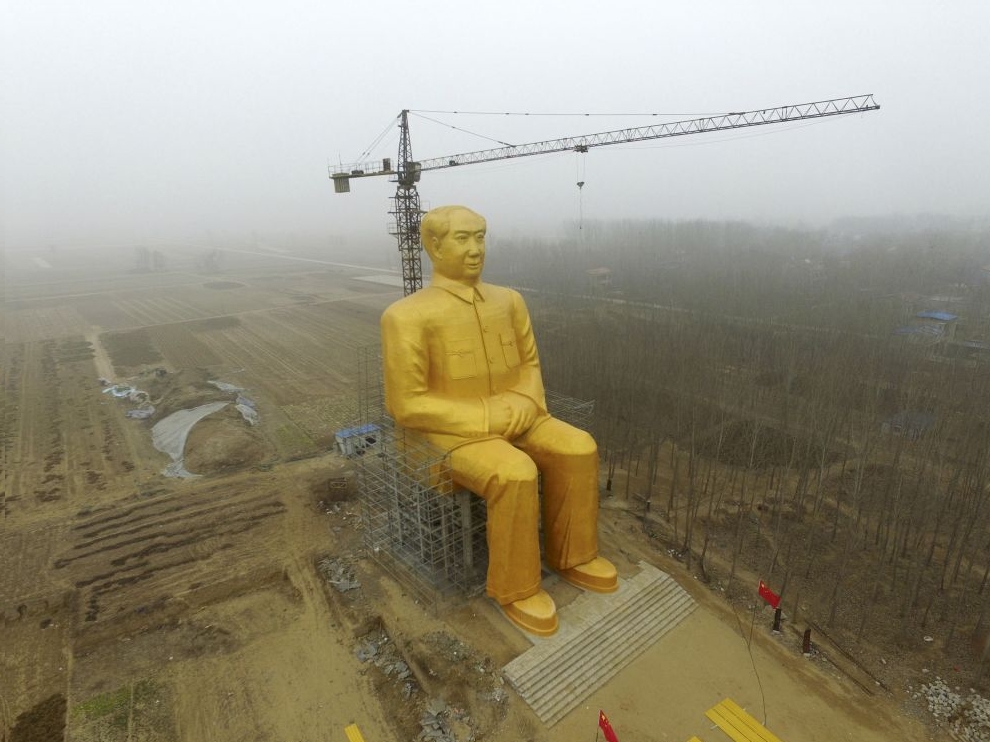 A crane is seen next to a giant statue of Chinese late chairman Mao Zedong under construction near crop fields in a village of Tongxu county, Henan province, China, January 4, 2016.
