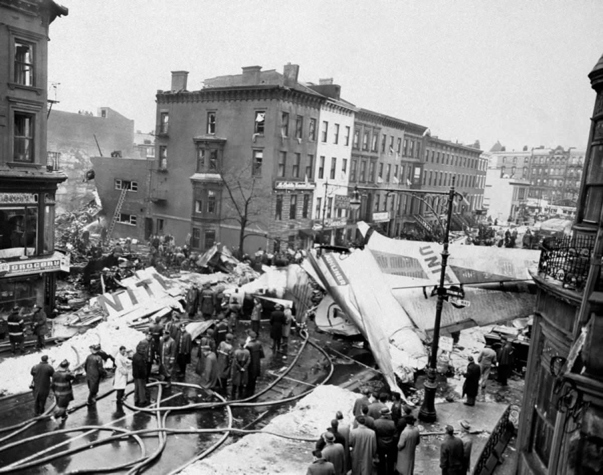 Workers work on finding survivors or the remains of the dead after a plane crashed in Brooklyn, NYC, US in 1960. This crash was known as the Park Slope Plane Crash. 2 Planes collided, both crashed in NYC, one here and the other on Stanton Island. All 128 people total on the 2 planes died, as well as 6 people on the ground. The crash was the worst in the US until 1968.
