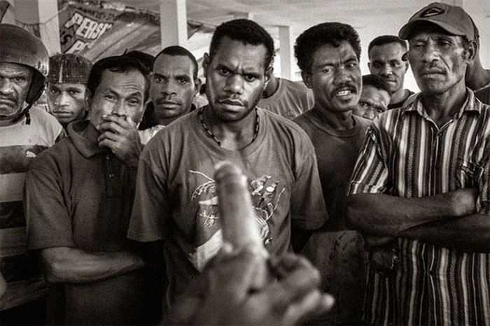 A group of men are shown how to use a condom for the first time in Papua, Indonesia.