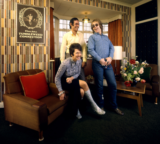 The former Reggie Dwight, later known as Elton John, laughs with his mom Sheila Fairebrother and her husband Fred, whom he affectionately called "Derf," Fred spelled backwards, in their suburban London apartment in 1970.