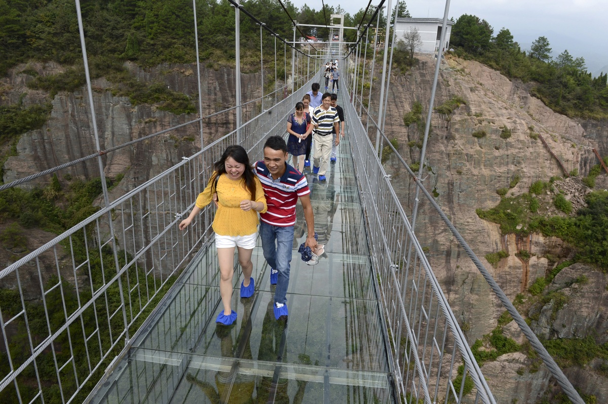 A group of brave tourists experience vertigo the hard way as they became the first visitors to cross a new 590 foot high glass-bottomed suspension bridge in China.