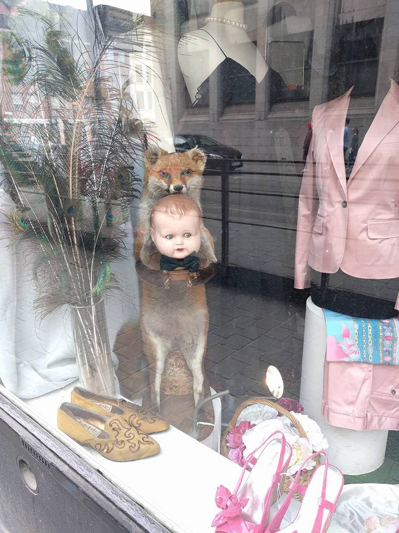 Strange scene in a window of a fox holding a baby in the display case.