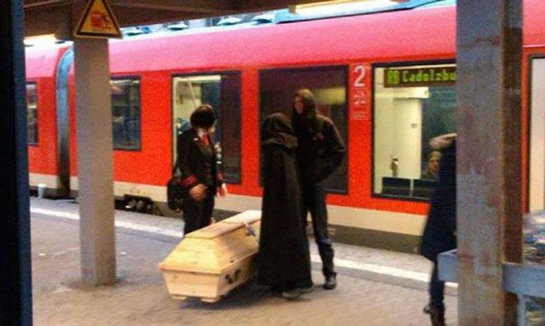 Dark looking crew with a white coffin about to get on the subway.