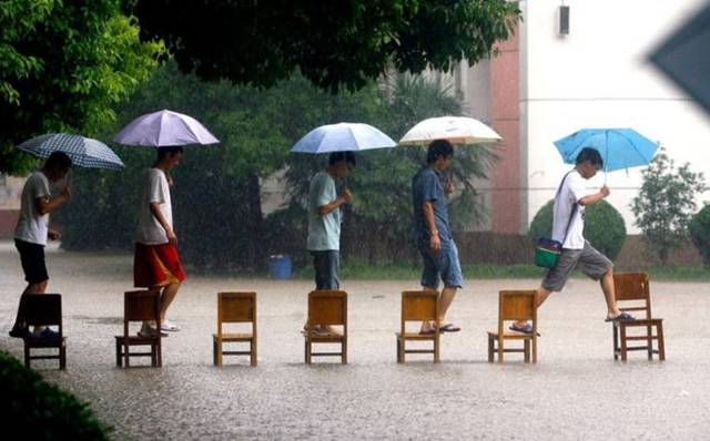 funny picture of kids using chairs to cross flooded street