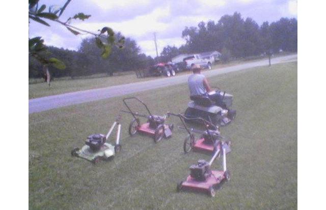 guy mowing his lawn by tying lawnmowers to the back of his riding mower in a flying v formation