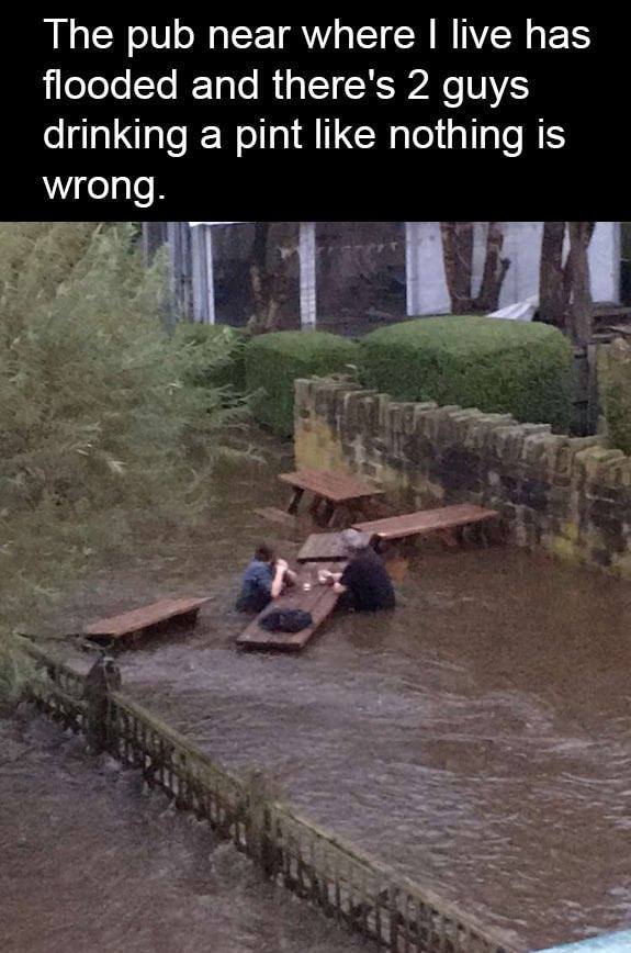 most british thing ever - The pub near where I live has flooded and there's 2 guys drinking a pint nothing is wrong.