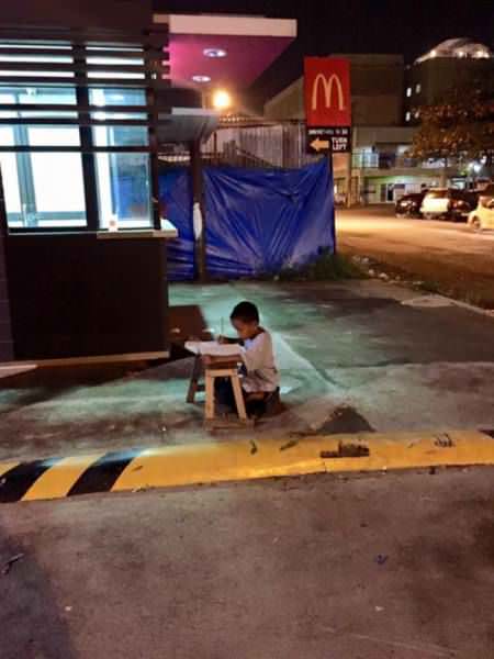 9-year-old Daniel Cabrera using light from McDonald’s to do his homework.