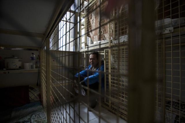 A man rests in his cage home, which he rents for HK$1,800 ($230) per month in Hong Kong.