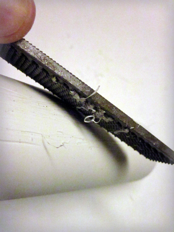Use the rasp side of the file to shred the PVC surface. Pull the file in many directions to give it an organic look. If the file's teeth get clogged, use a wire brush to quickly clear them.