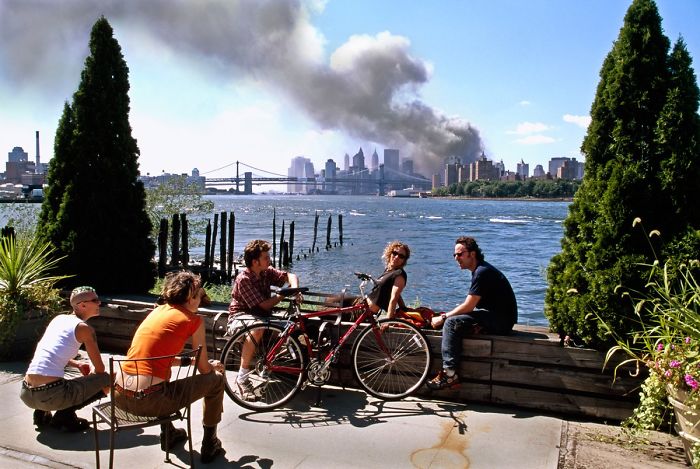 9/11 photo of young people lounging on the other side of the river as the towers collapsed.
