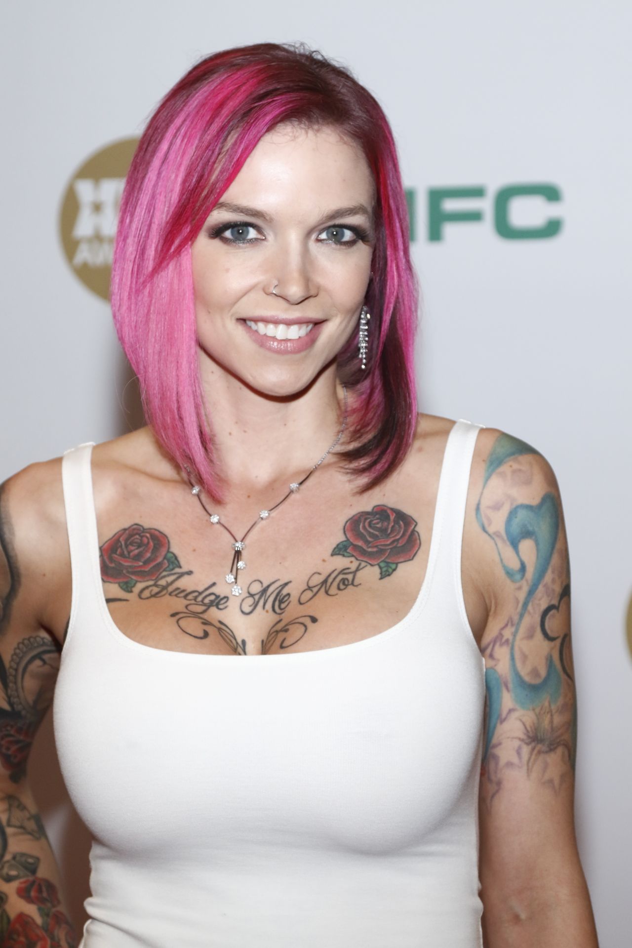 photo of Anna Bell Peaks in a white shirt with pink hair. 
