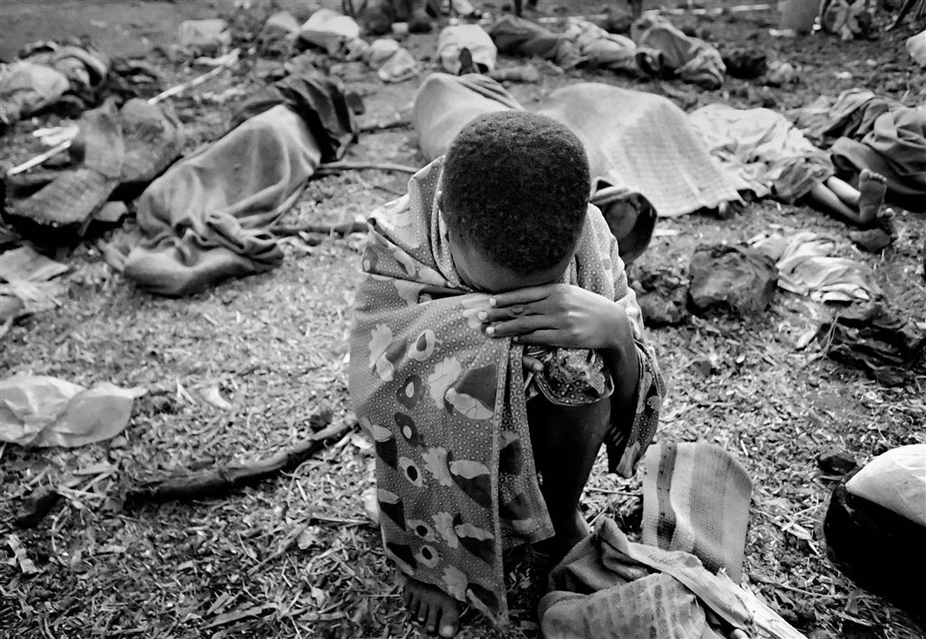 A boy cries near the bodies of his family who were murdered during the Rwandan Genocide in 1994.