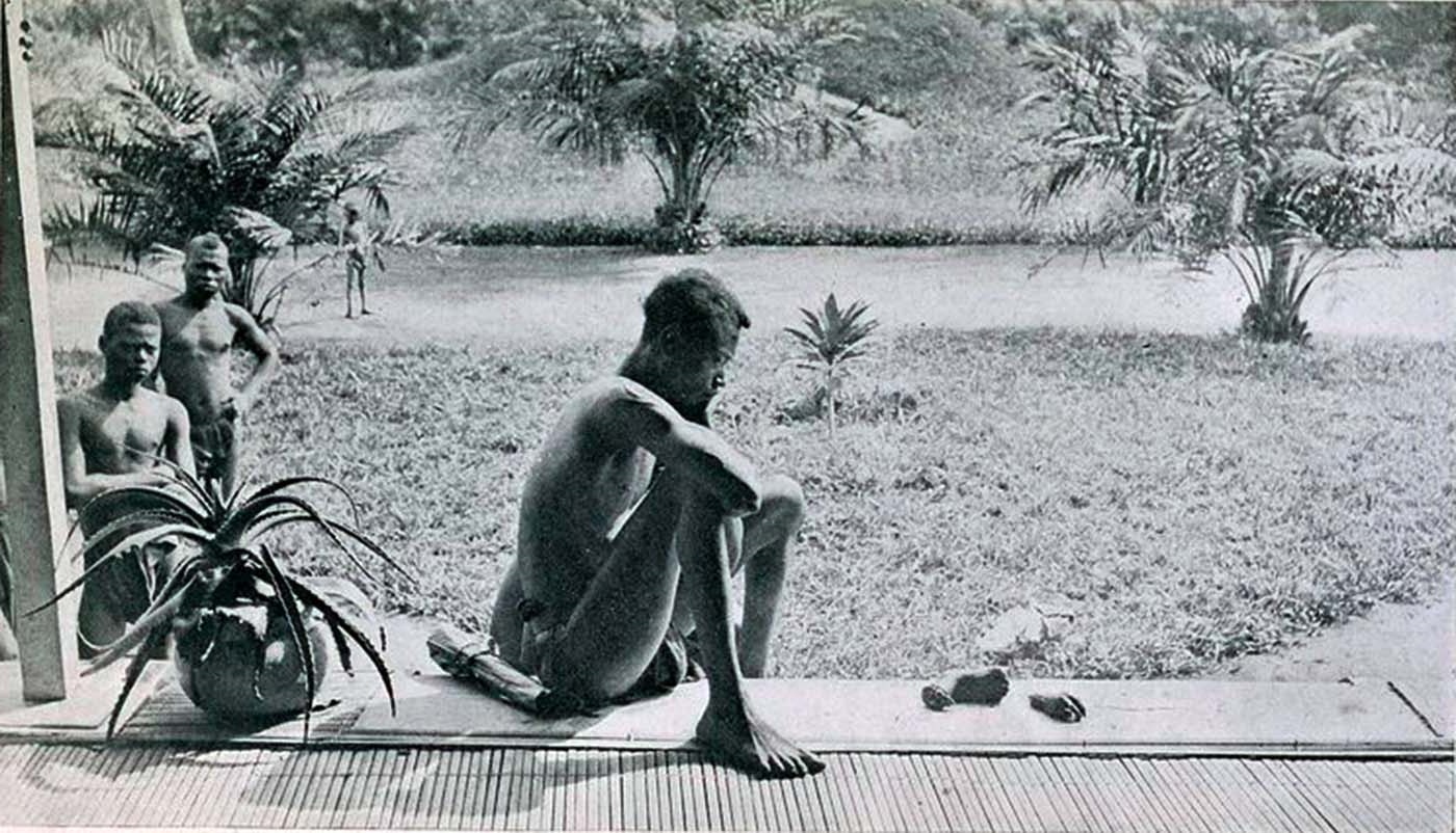 A father has a blank stare as he looks at a hand and foot that has been cut off one of his children as punishment for not meeting a quota of goods in the Belgian colony of the Congo in 1904. The tribesmen were basically slaves, working for no wages, to meet high demands, and were punished with lost limbs of themselves or family members for not meeting quotas. It was a brutal and dark time in Belgian and Congolese history.