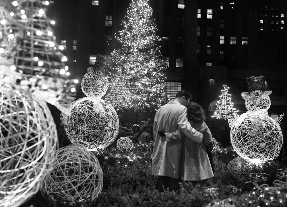 A pair of lovers are entranced by the beauty of the scene after the traditional Rockefeller Center Christmas tree was lighted. The couple is framed by wire snowmen on the Channel Gardens. The 50-year-old, 67-foot white spruce is the 30th tree to be raised in the Center for Christmas.