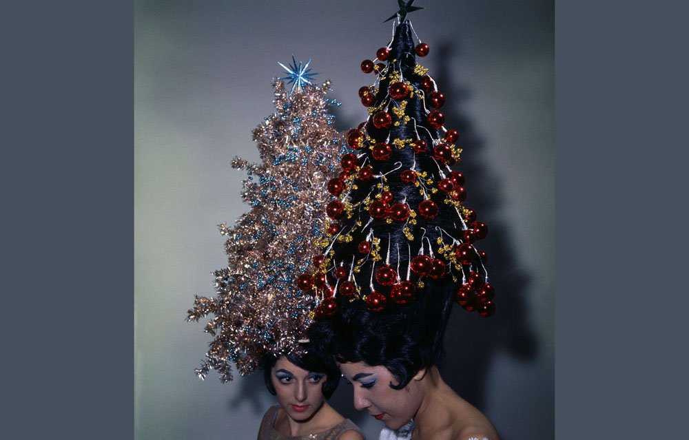 Two young women display their holiday hairdos, each with 42-inch hair decorated with tinsel and ornaments. Claudette Ackrich’s hair is decorated with tinsel, and Giselle Roc’s hairstyle consists of Christmas tree balls. Both women have never had their hair cut.