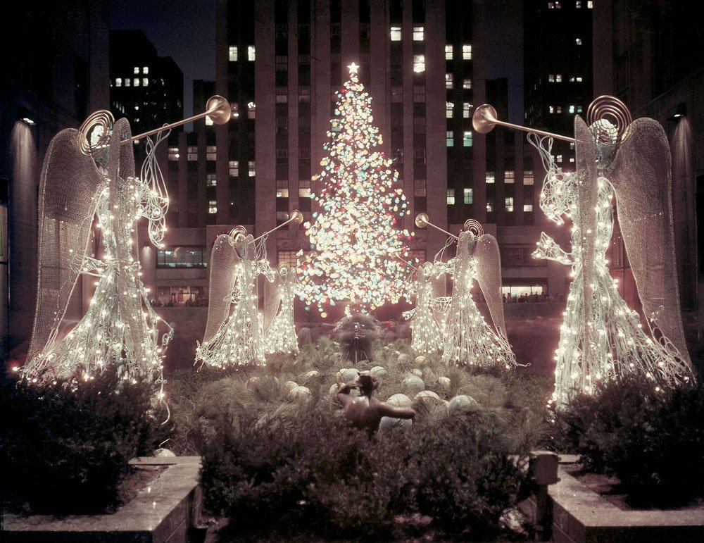 This is a night view of the famous christmas tree at Rockefeller Center, seen through the Channel Gardens from Fifth Avenue, in December 1955.