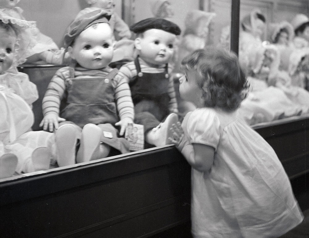 Christmas may be three weeks away for us, but it is here for the children who tour Toyland in Bamberger’s Department Store in Newark laughing, lingering and longing. The Moppets make an interesting and sometimes touching study. Here, a little girl has fallen in love with the dolls. Can you imagine anything as wistful as the eyes of the little girl as she peers into the case. Let’s hope they all get what they want from Santa.