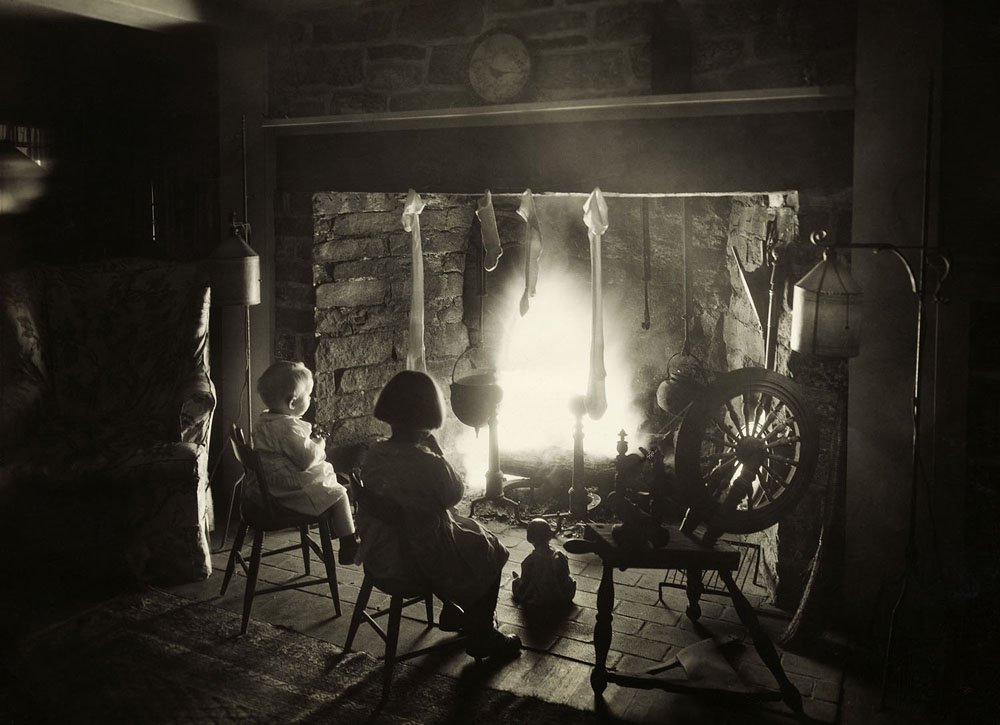 Children sit in front of the fireplace on the night before Christmas. Undated photograph.