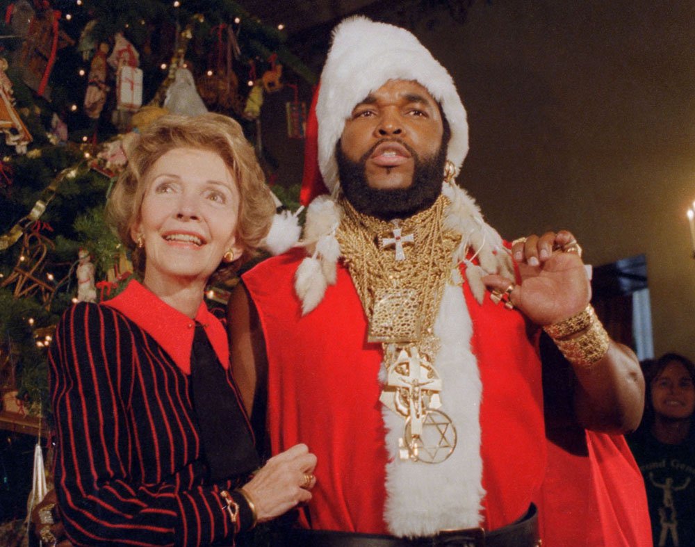 Washington, D.C.: Mr. T, of the television show the A-Team, poses as Santa Claus to help First Lady Nancy Reagan unveil the White House Christmas decorations. December 12, 1983.